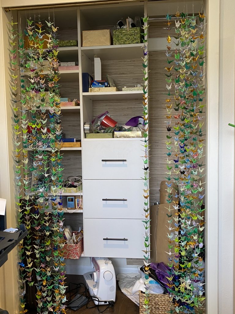 The closet for storage: strings of paper cranes in front, with colored boxes to hold supplies.