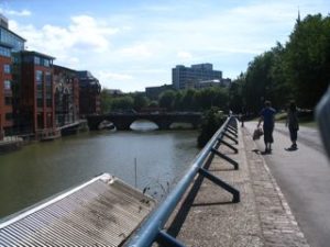 Bristol's floating harbor: a wide canal, with modern buildings on one side and a stone walking path on the other.