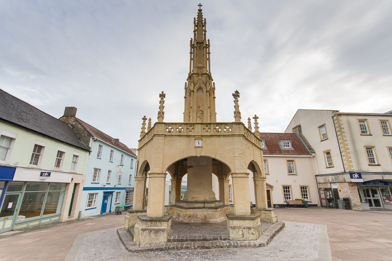 Market cross: A medieval octoganal structure, gazebo like with a roof, but open to the air, with a high, pointed spire and medieval details.