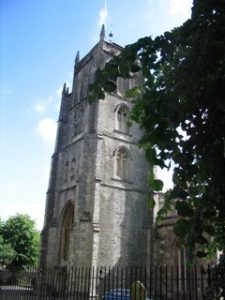 A large gray spire going up several stories, surrounded by a church yard iron fence