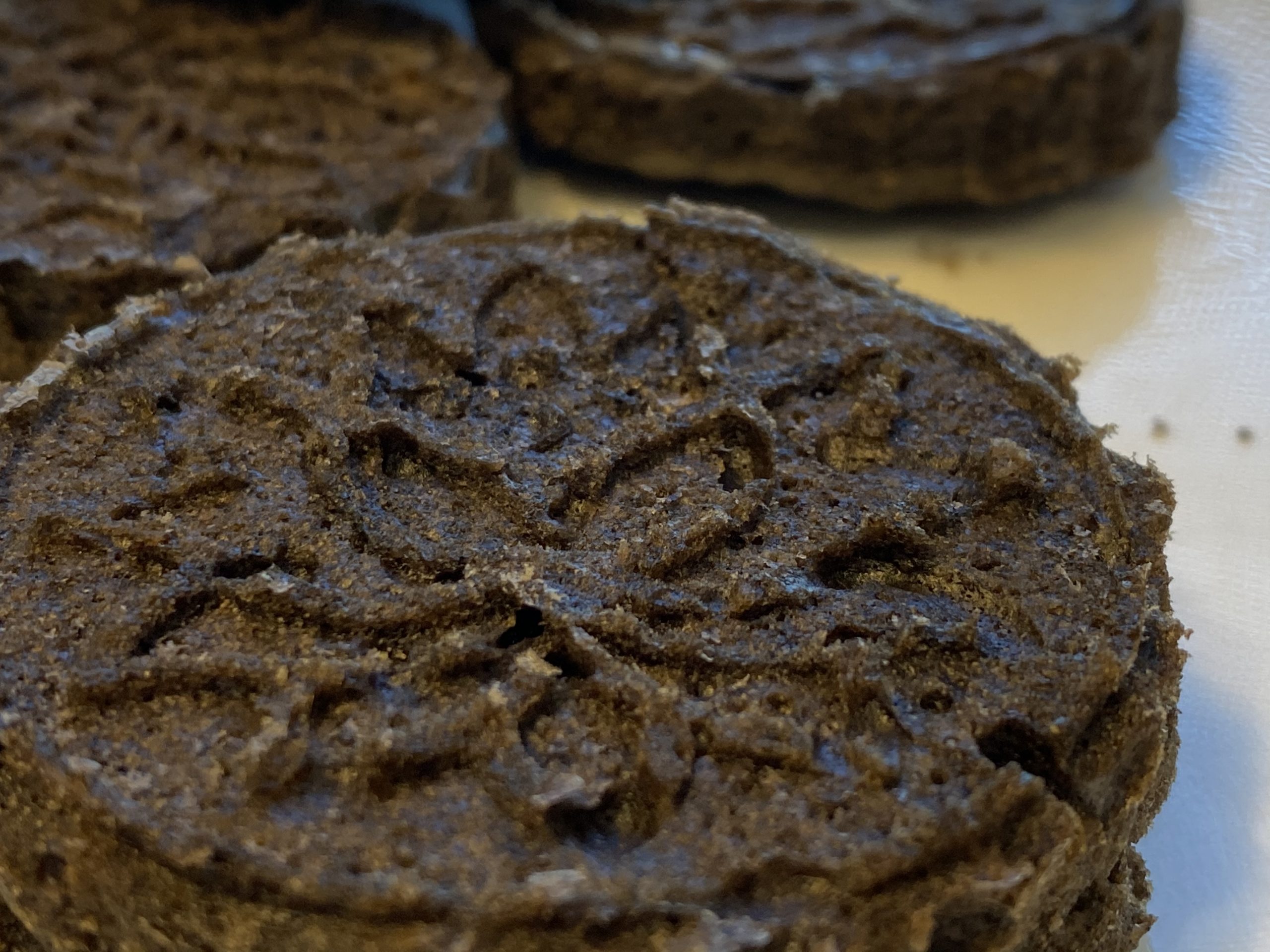 Picture of black sesame pound cake: round dark brown cakes with a delicate lotus pattern stamped on top.