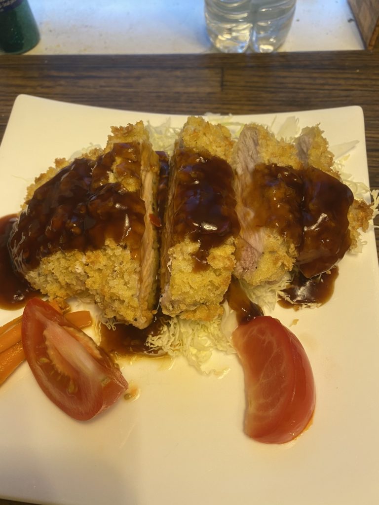 A cutlet of pork drizzled with Wedgeford Brown, over shredded cabbage, with tomato wedges