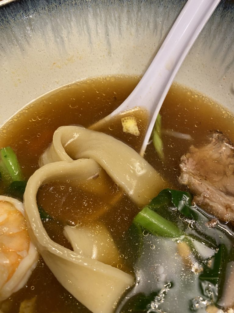 Noodles in a brown broth with other things on the side: greens, shrimp, pork...